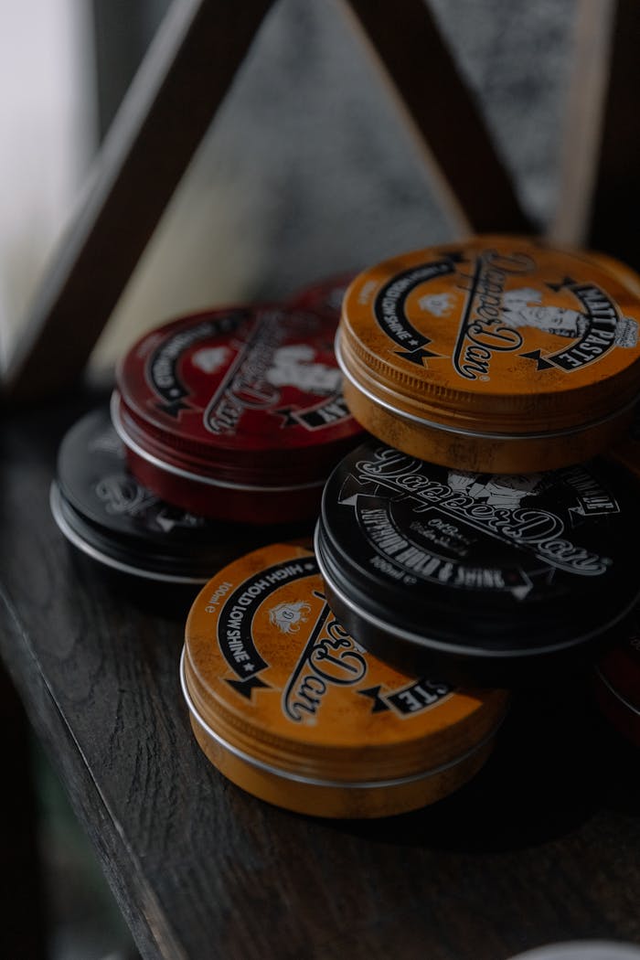 The Art of Drawing Readers In: Your attractive post title goes here A collection of colorful hair product tins neatly stacked on a wooden shelf.