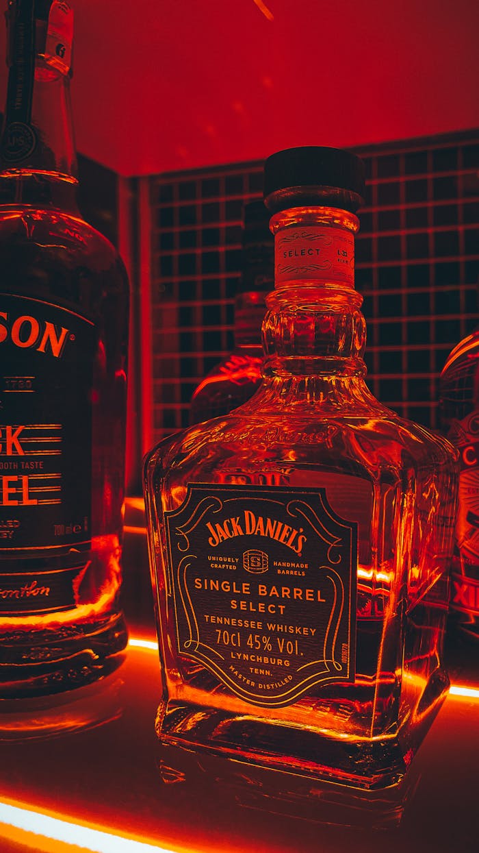 Mastering the First Impression: Your intriguing post title goes here Close-up of branded whiskey bottles on an illuminated bar shelf with a warm ambiance.